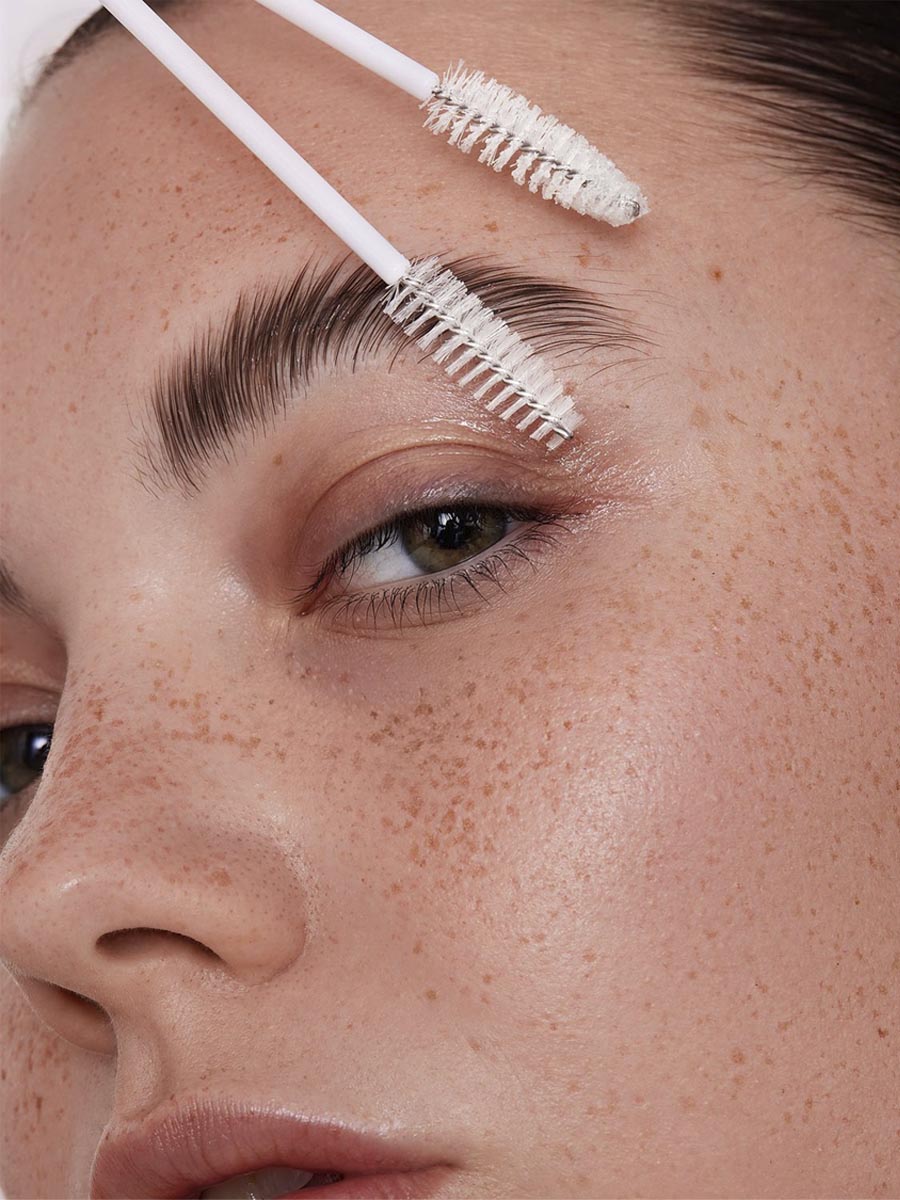 Primer plano de ojos, cejas y pestañas naturales con luz cálida y piel con pecas.