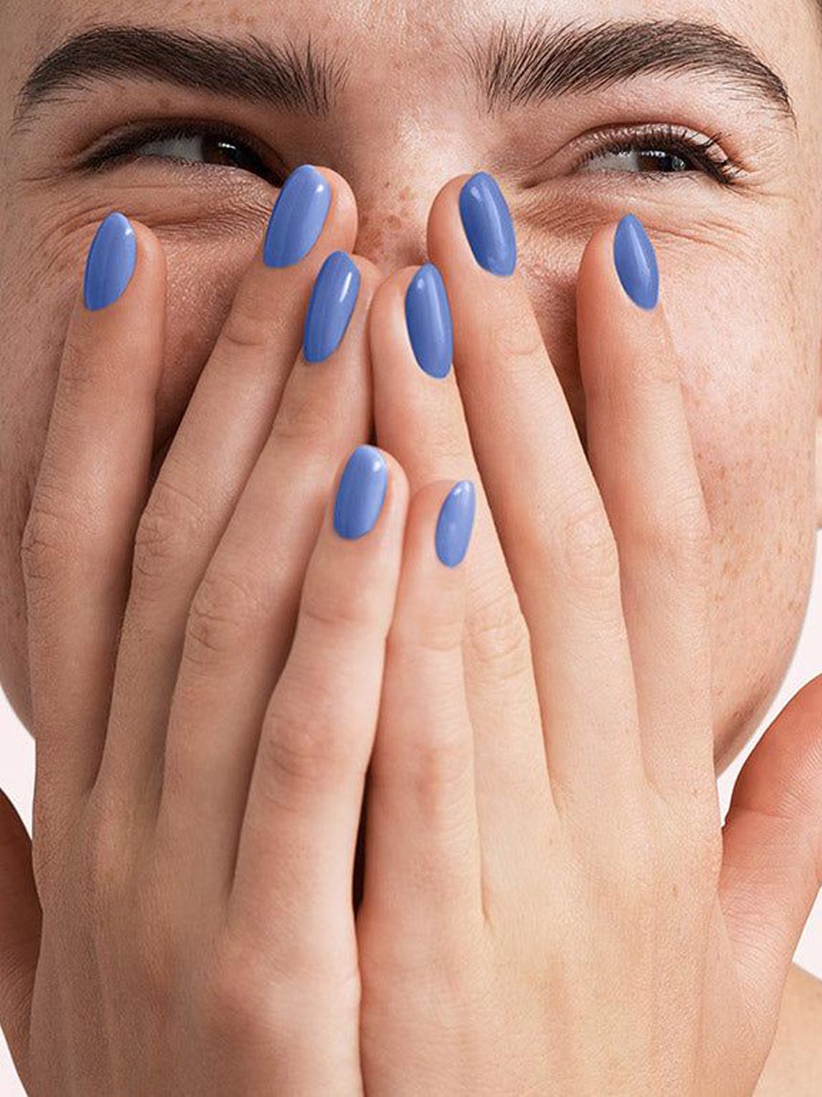 Mano con manicura nude clara y acabado brillante, con camisa blanca. Imagen de los servicios de manicura de KOLORAMA.