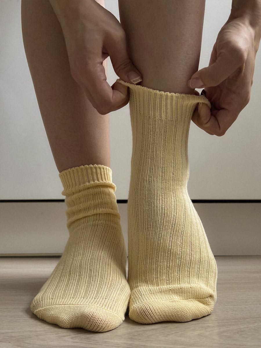 Pies con pedicura en esmalte burdeos sobre tejido blanco, en una fotografía de estilo lifestyle.