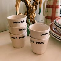 vaso de cerámica para espresso con el mensaje Drama Queen, apilado junto a otros vasos con mensajes en un ambiente lifestyle Kolorama.